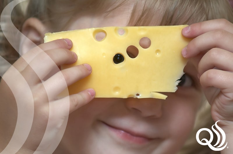 Yeast in Cheese Production - Little girl peeking through cheese whole